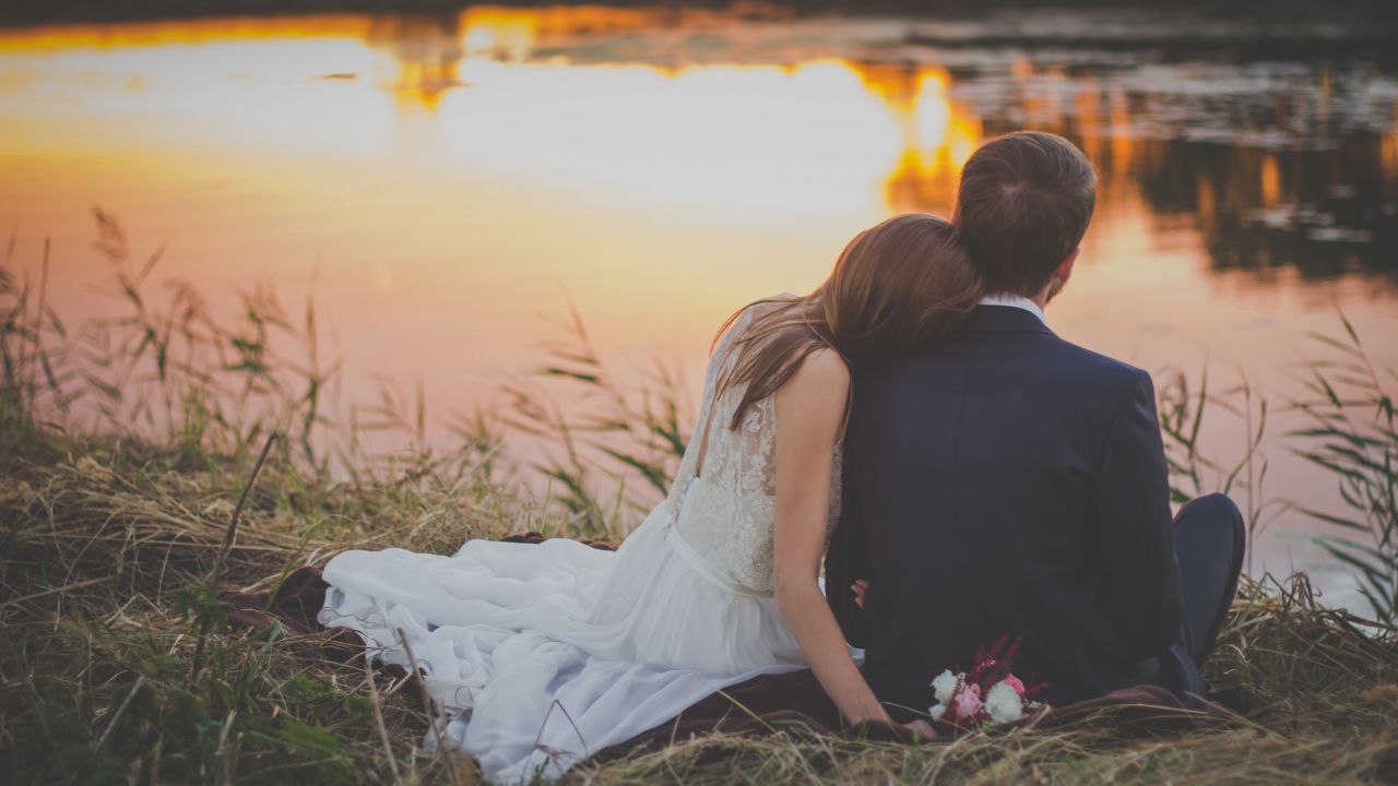 Wedding couple sitting by lake