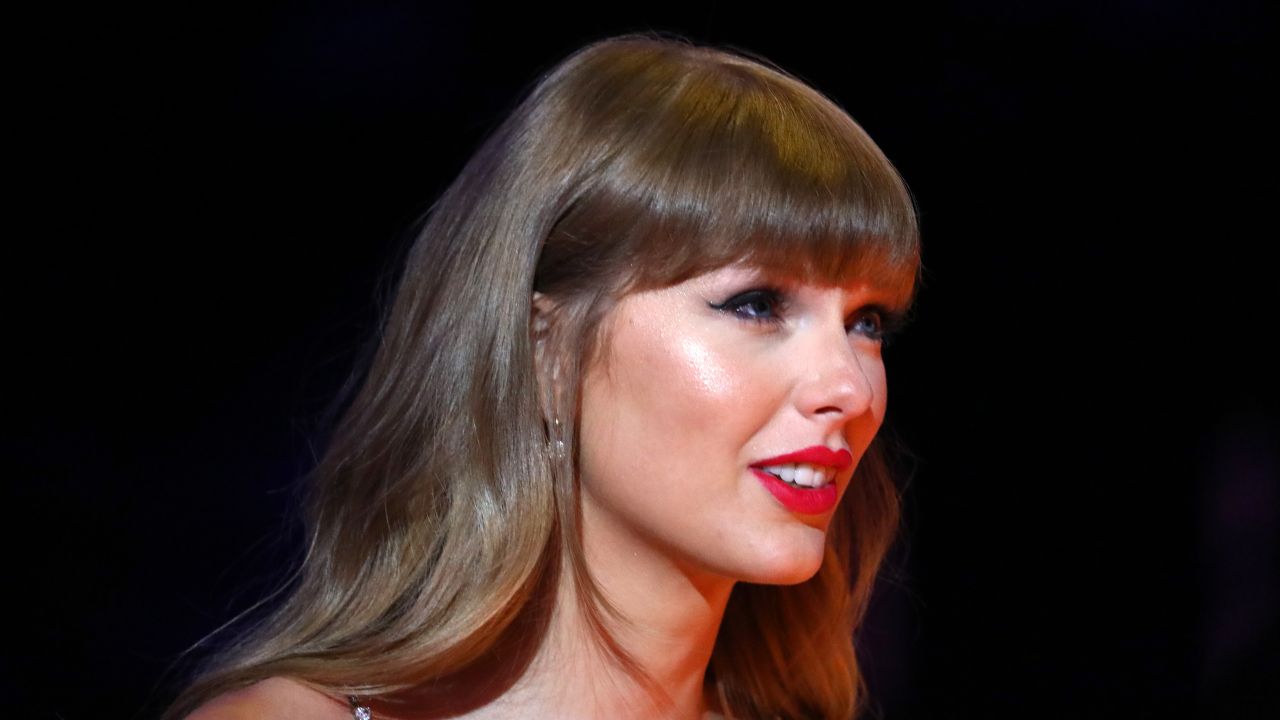 A side profile headshot of Taylor Swift wearing red lipstick