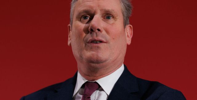 Headshot of Labour leader Sir Keir Starmer speaking at a conference against a red background