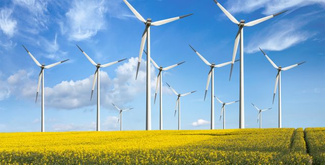 An onshore wind farm amid a field of yellow rapeseed on a sunny day