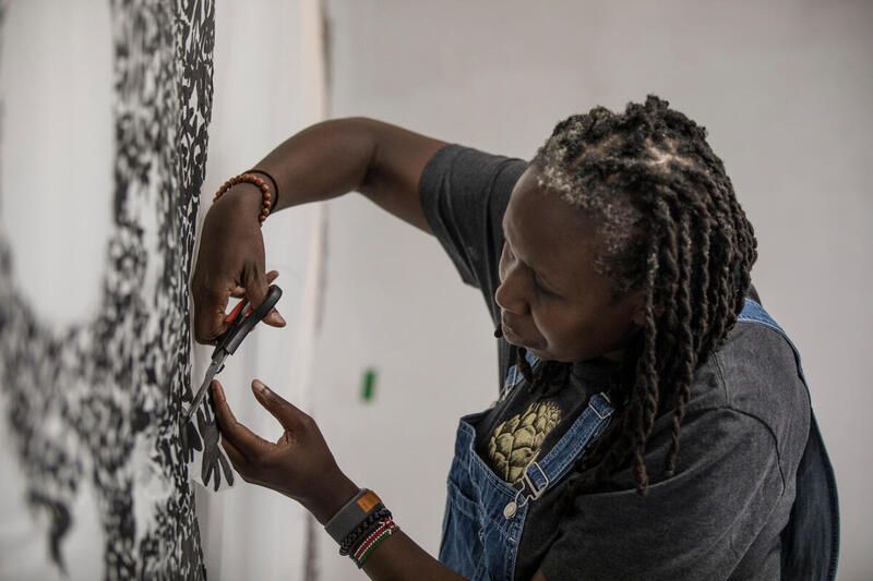 A close up shot of artist JC Niala trimming her artwork with a pair of scissors.