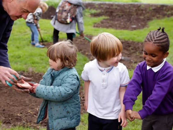 Gardener handing out seeds to young children