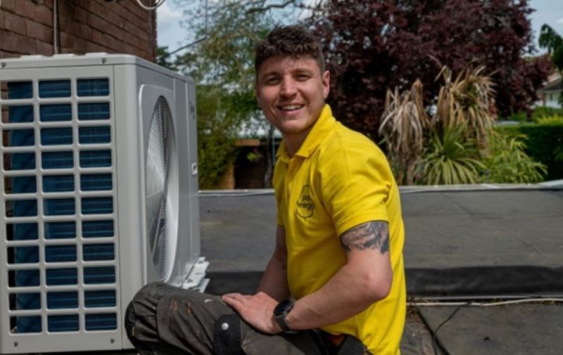 A man kneeling next to a heat pump