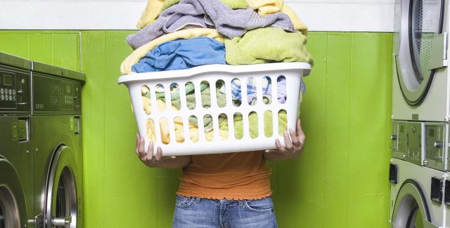 Holding overflowing washing basket at laundrette