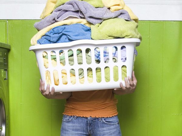 Holding overflowing washing basket at laundrette