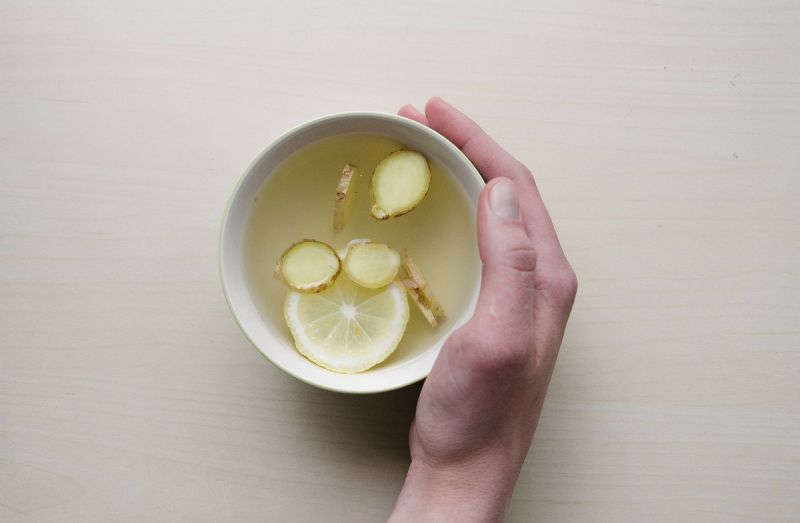 Hand cupped round a bowl of hot lemon, honey and ginger