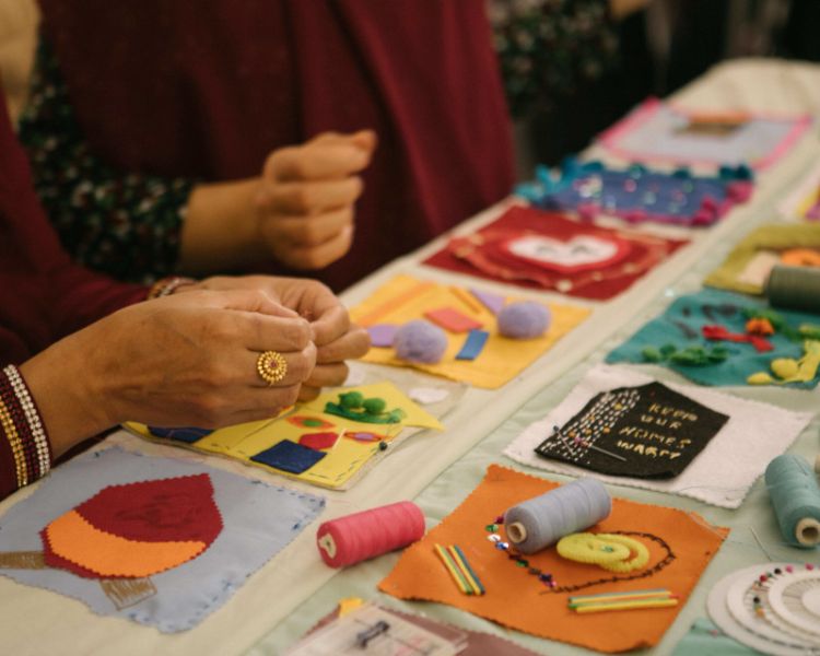 A close up of a woman's hand sewing detail onto a patch