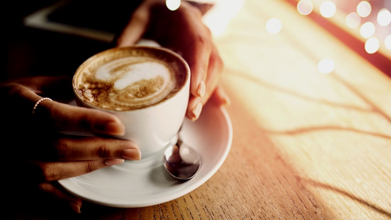 photo of hands holding ceramic coffee cup