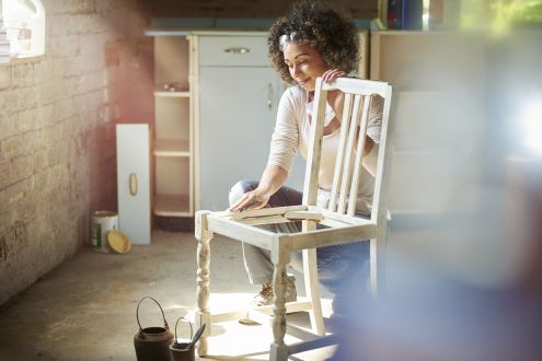 photo of woman sanding wooden chair