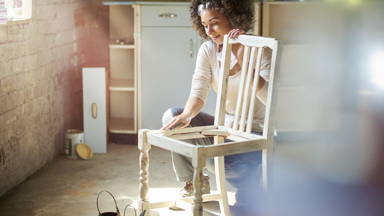 photo of woman sanding wooden chair