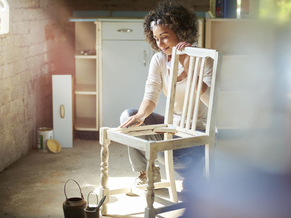 photo of woman sanding wooden chair