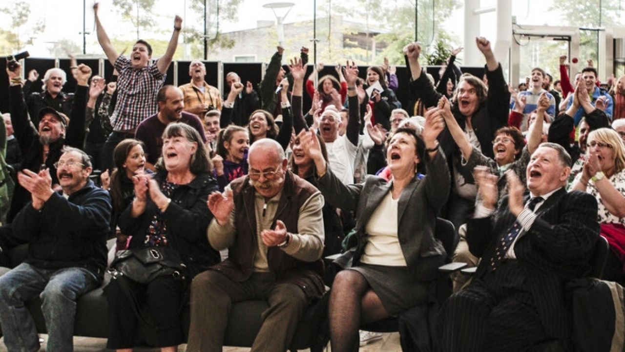 Large group of people in hall cheering at outcome of Nant Llesg coalmine planning decision