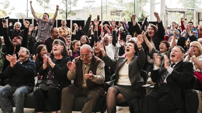 Large group of people in hall cheering at outcome of Nant Llesg coalmine planning decision