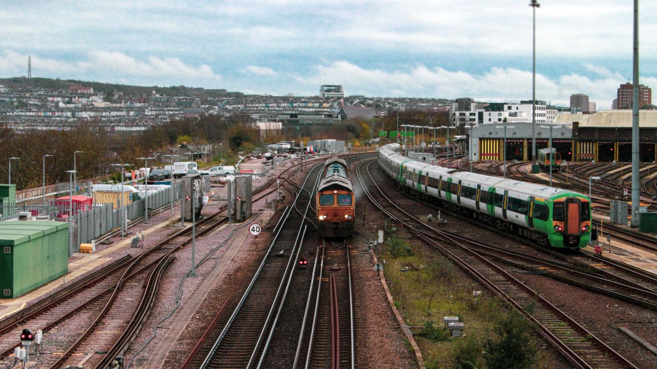Two trains at Brighton Station with houses in the horizon 