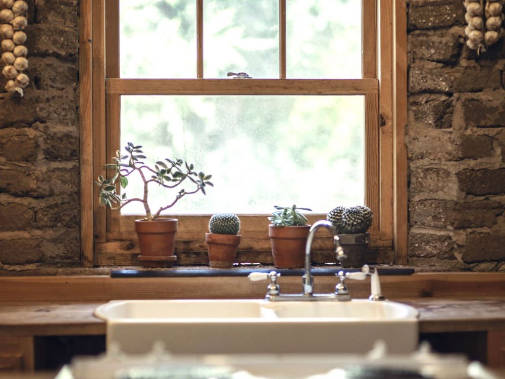 A white enamel kitchen sink below a window ledge