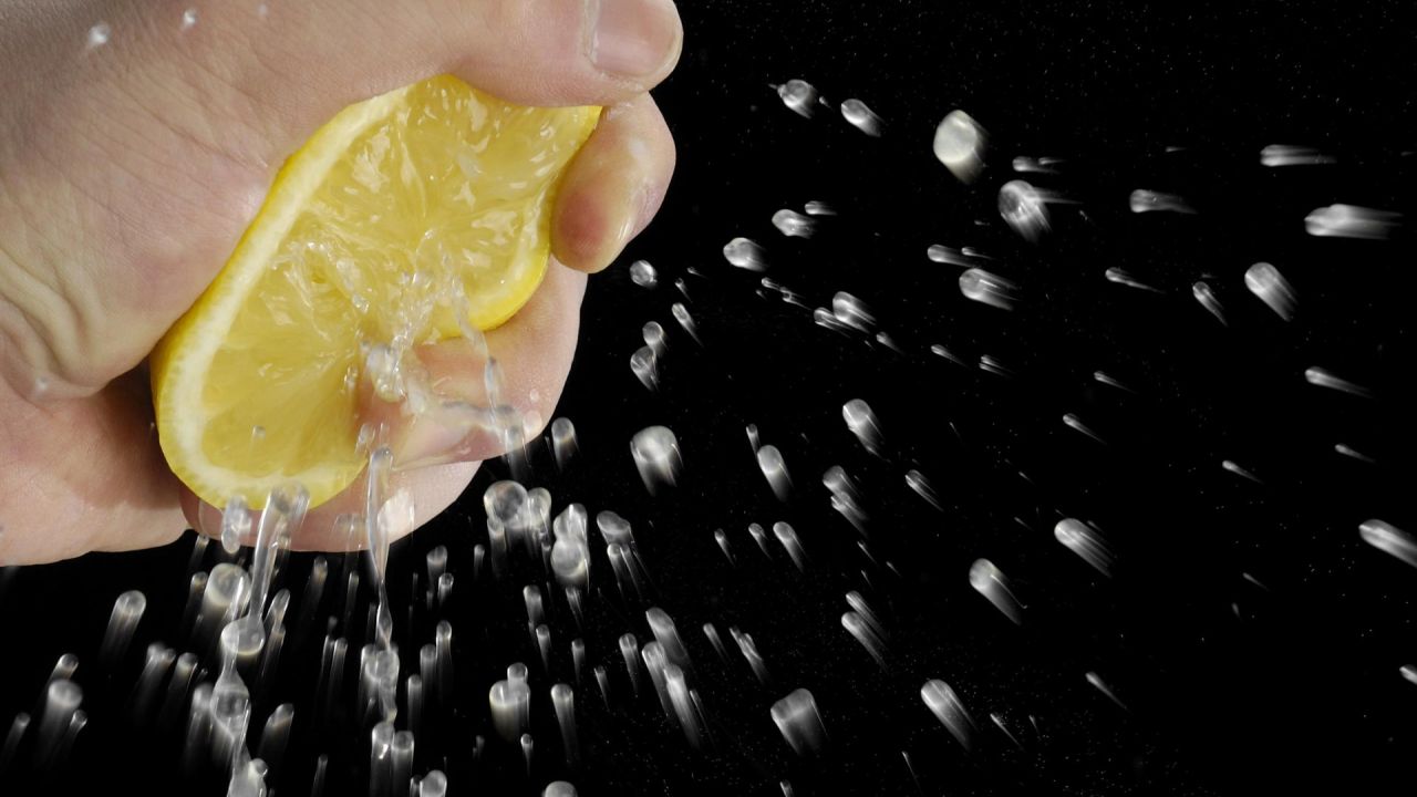 Hand squeezing juice from half a lemon