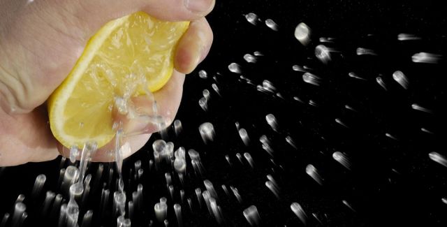 Hand squeezing juice from half a lemon