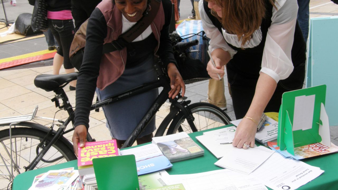 A cyclist looking at the materials on a Friends of the Earth local group stall