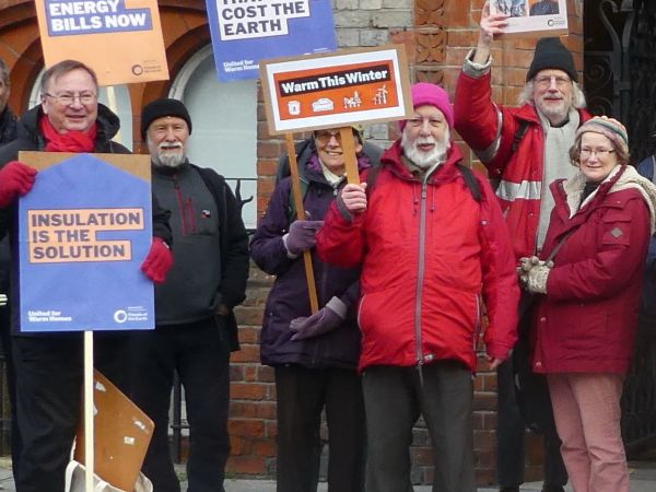 A group of campaigners holding placards demanding insulation for warm homes