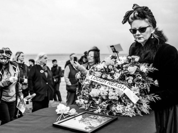 A women laying a wreath on a coffin for Lough Neagh