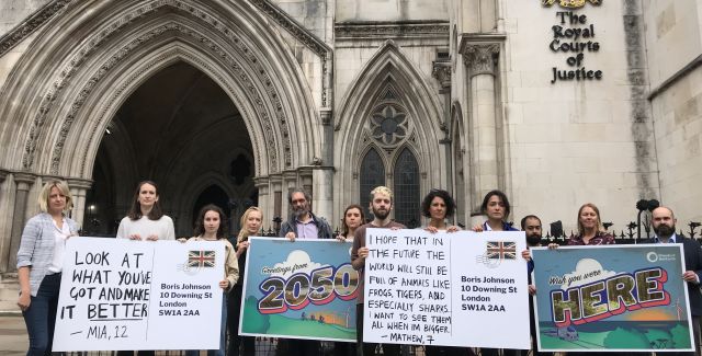 People demonstrating with giant postcards outside the Royal Courts of Justice