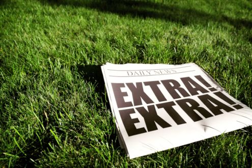Newspaper with Extra Extra headline laying on a lawn
