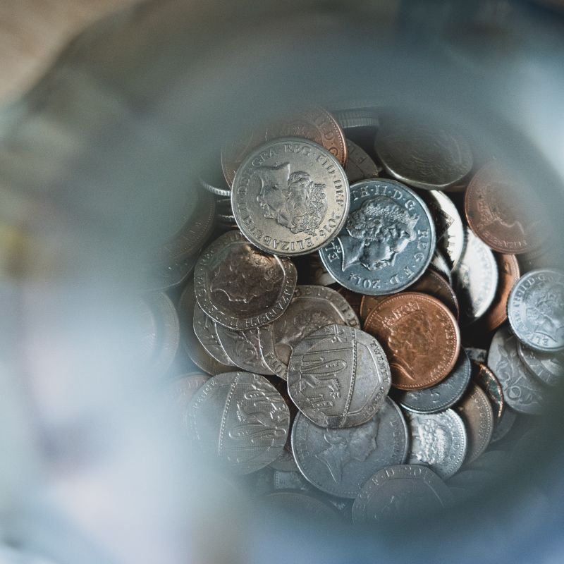A close up shot of inside a jar with coins -  50p, 20p, 10p, 2p and 1p pieces 