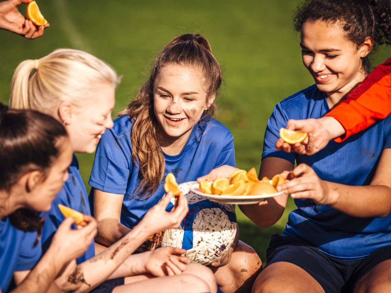 Girls sports team eating oranges at half time