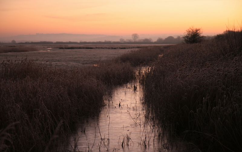 Otmoor at dawn. Looking across wetlands. Flooded ditch leads from foreground to horizon.