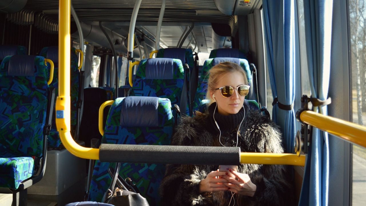 photo of passenger on a bus with earphones and sunglasses