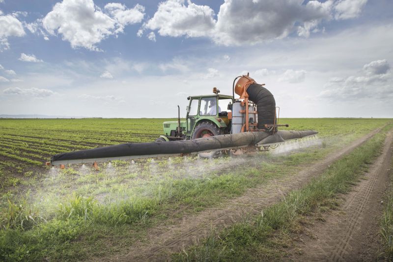 A tractor spraying pesticides onto a field
