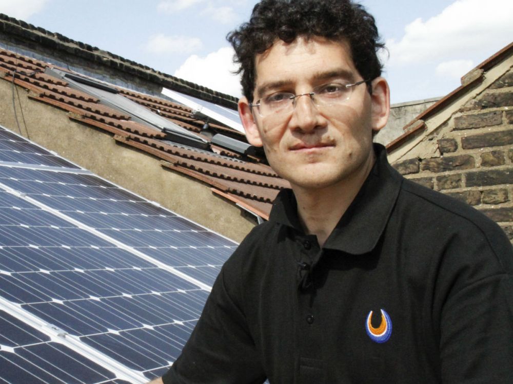 Phil Michaels next to solar panels on a terrace house roof