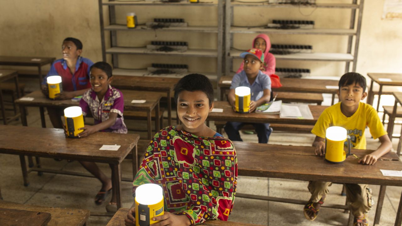 Smiling children behind desk in Bangladeshi school with light up lanterns