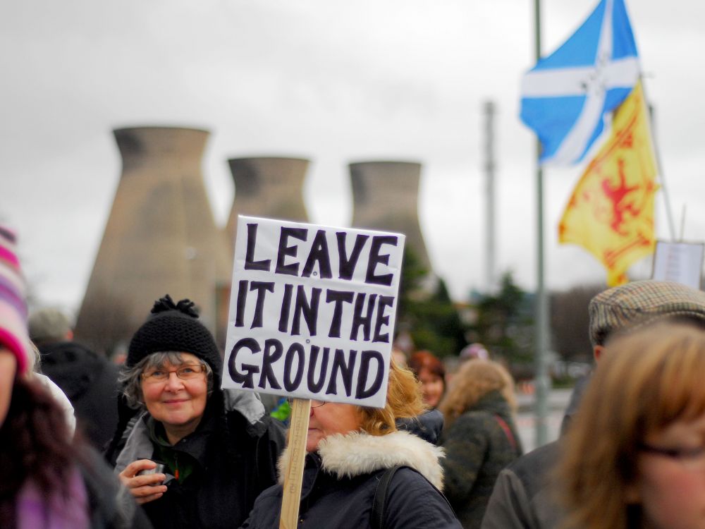 Fracking protest with a woman holding a sign which reads 'leave it in the ground'