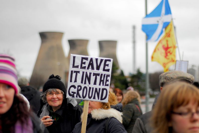 Fracking protest with a woman holding a sign which reads 'leave it in the ground'
