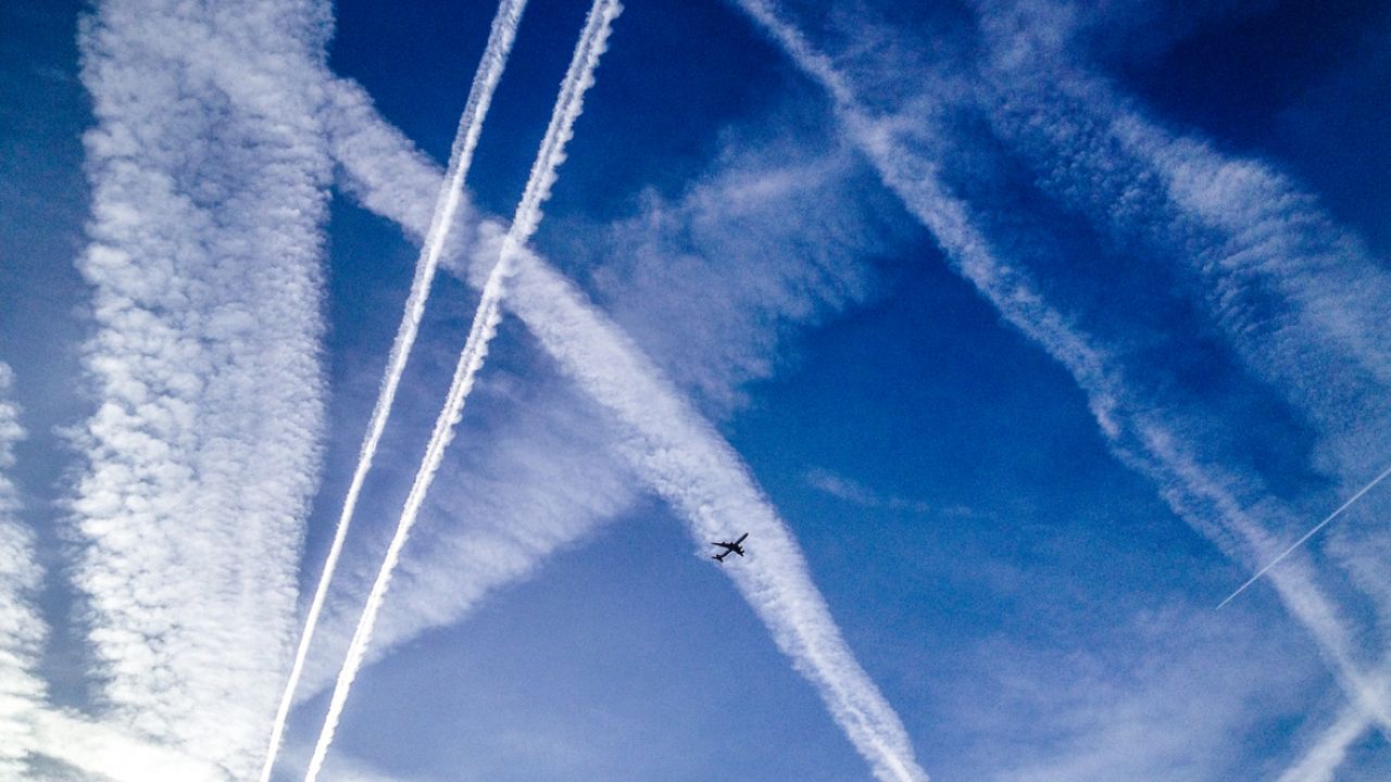photo of aeroplane in blue sky with contrails