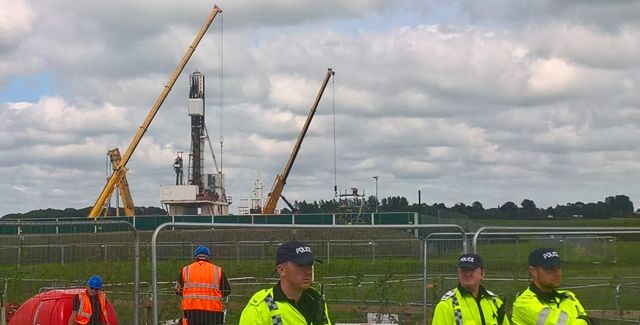 3 police guard the fracking site at Preston New Road, Preston, Lancashire. Site and 2 workmen in background.