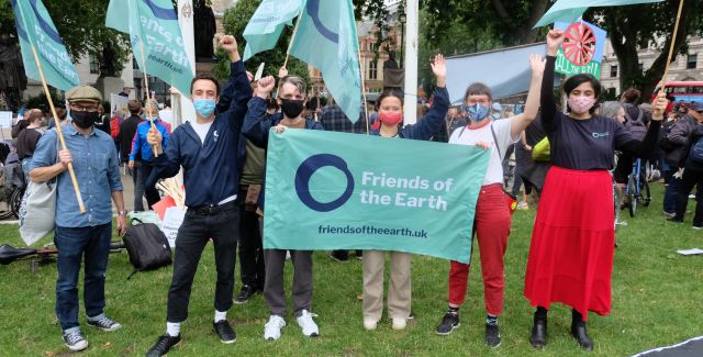Group of people holding banners and flags at a protest and raising their fists