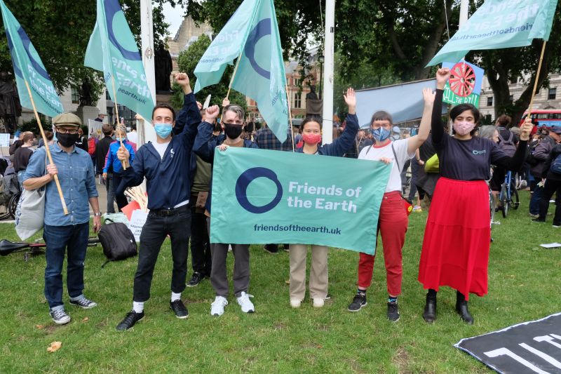 Group of people holding banners and flags at a protest and raising their fists