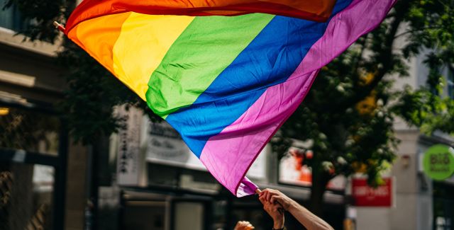 Pride rainbow flag over a crowd of people