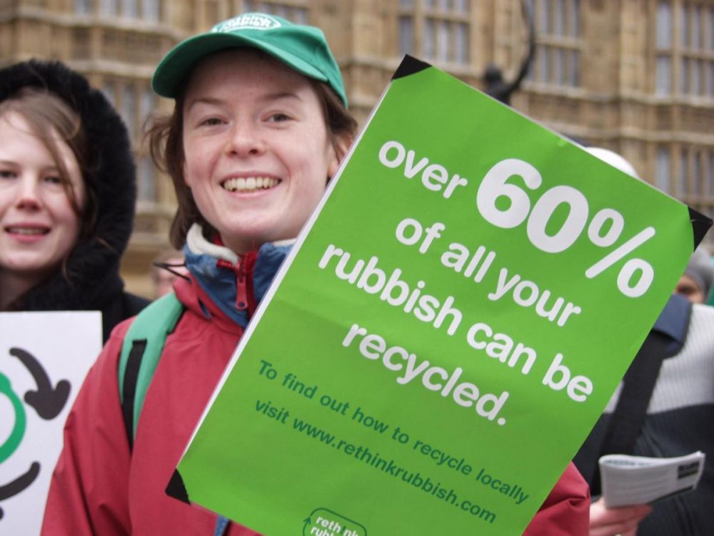 Person holding a banner that reads "Over 60% of your rubbish can be recycled"