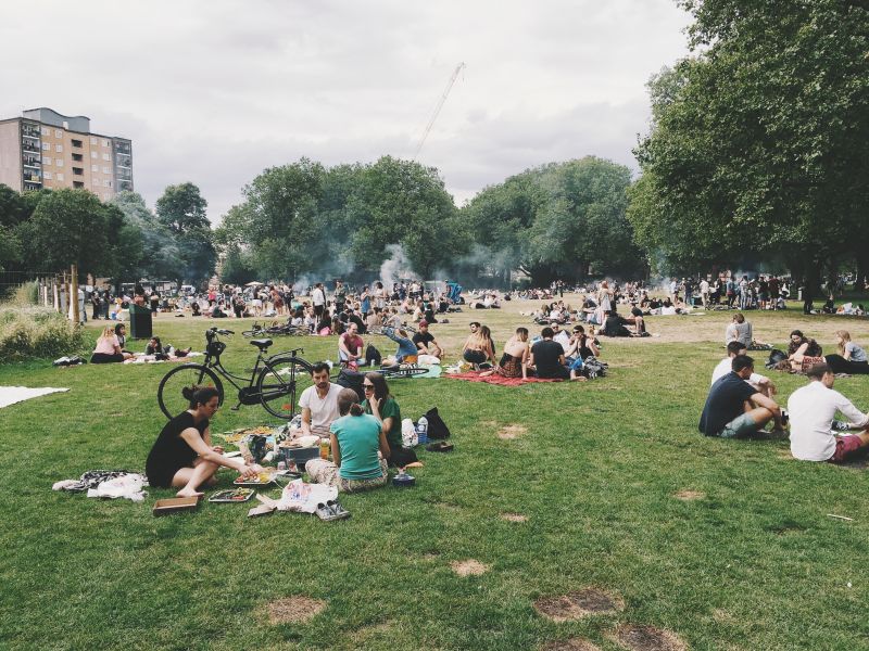 People picnicking and barbecuing in park in hot weather
