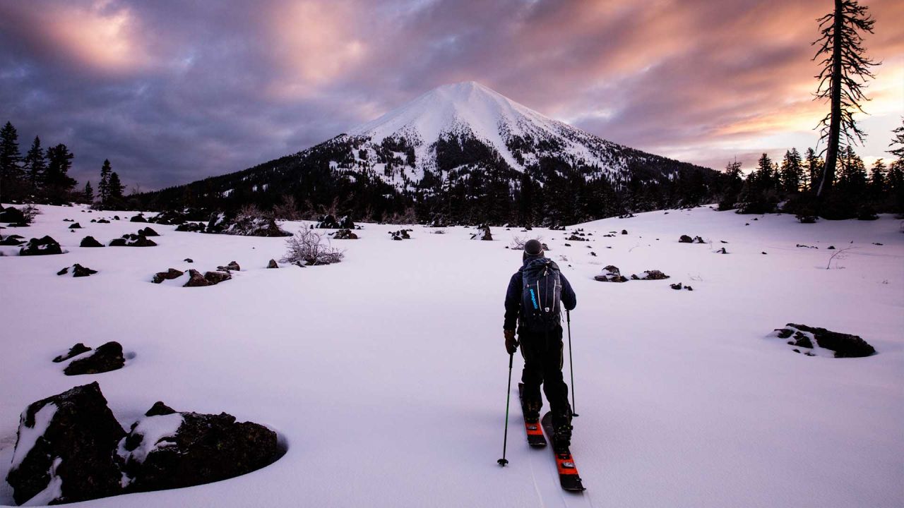 Cross-country skier in Patagonia clothes in front of mountain at sunset