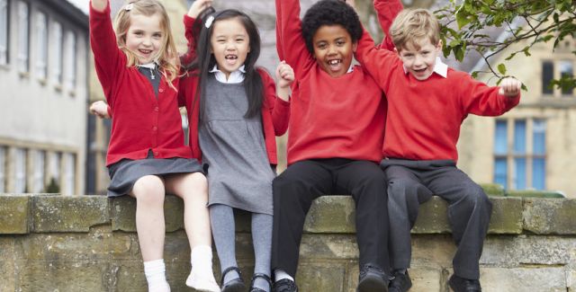 photo of four school children sitting on a wall