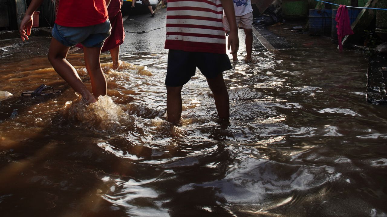 People in shorts walk through flooded streets in Indonesia