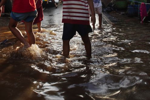 People in shorts walk through flooded streets in Indonesia