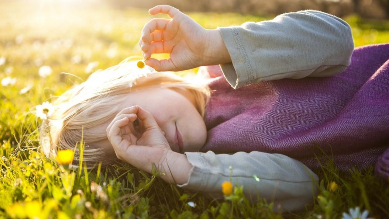 photo of child lying on a lawn