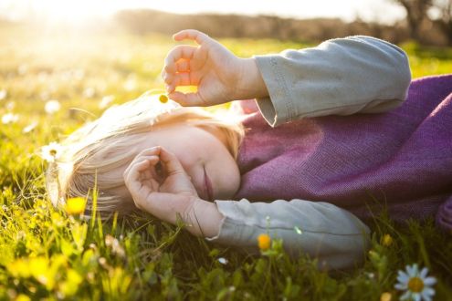 photo of child lying on a lawn