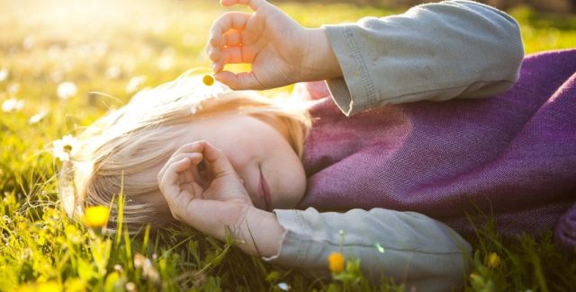 photo of child lying on a lawn