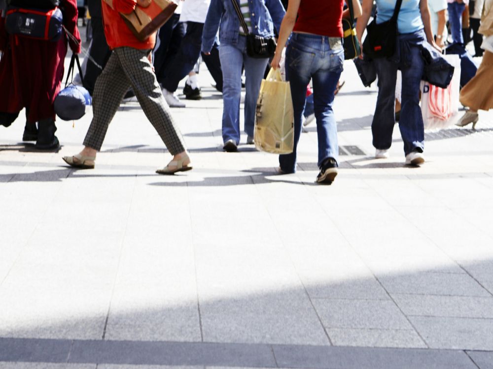 Crowd of people walking along a pavement with shopping bags